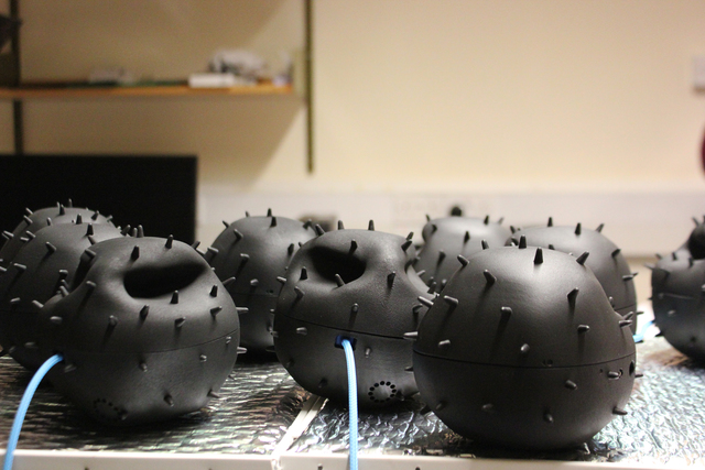 Nine sensor arrays contained in black, spiny casings, two of which trail a blue wire sitting on table.