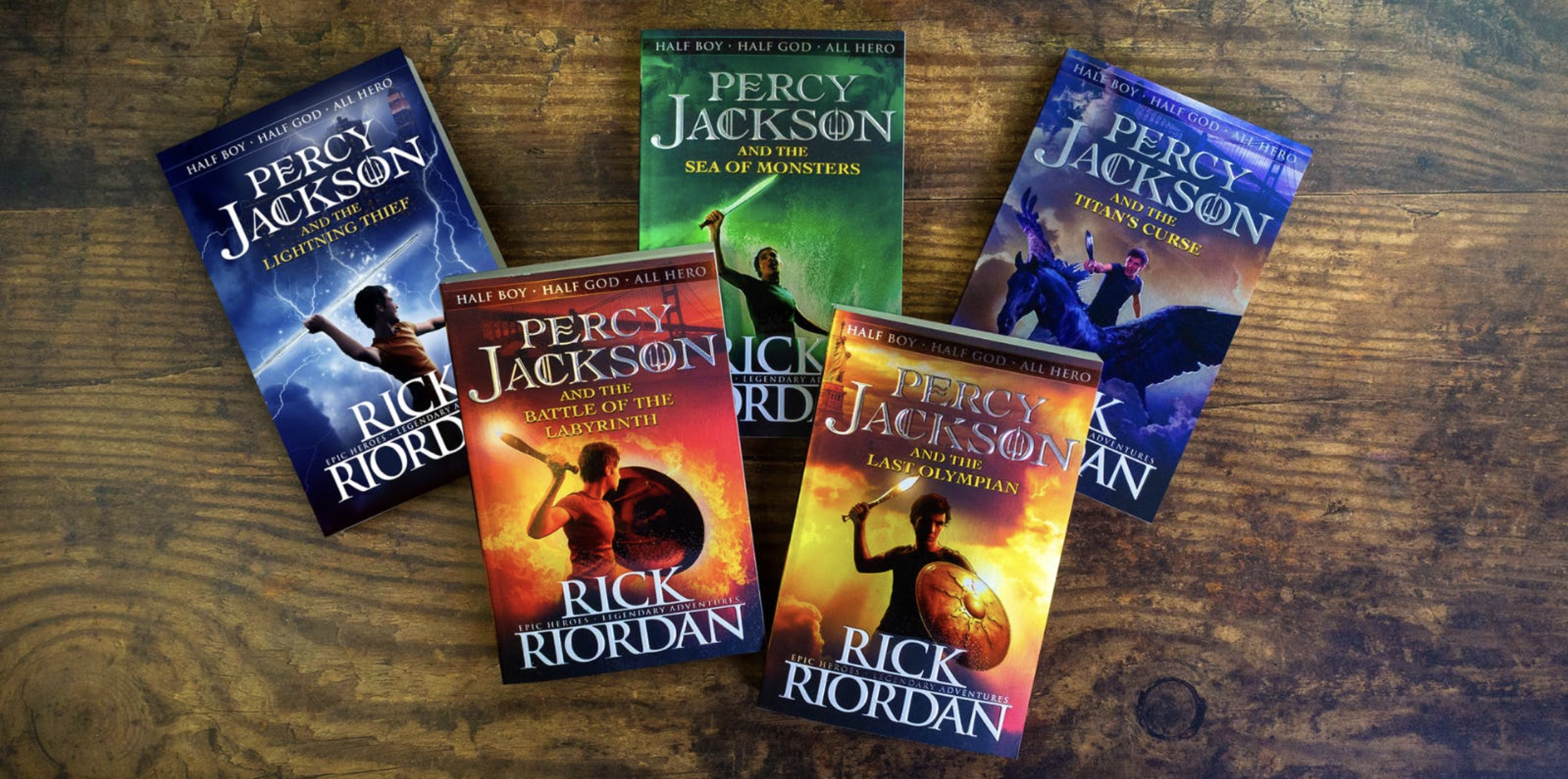 This picture includes all five of the "Percy Jackson & the Olympians" books on a table in order from left to right: The Lightning Thief, The Sea of Monsters, The Titan's Curse, The Battle of the Labyrinth, The Last Olympian.