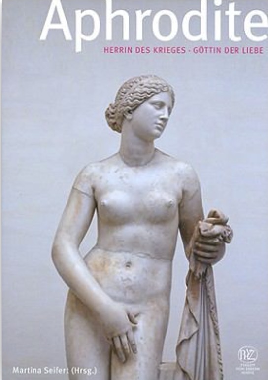 Book cover showing a marble statue of Aphrodite standing nude, holding a piece of cloth in her left hand. The background is light purple, and the title “Aphrodite: Herrin des Krieges, Göttin der Liebe” appears at the top in white and pink font.