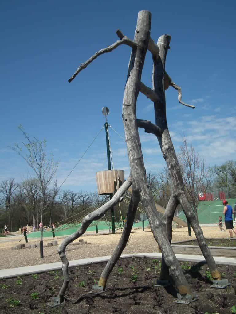 Whimsical ladders are hewn from tree branches in the snakes and ladders themed playground.