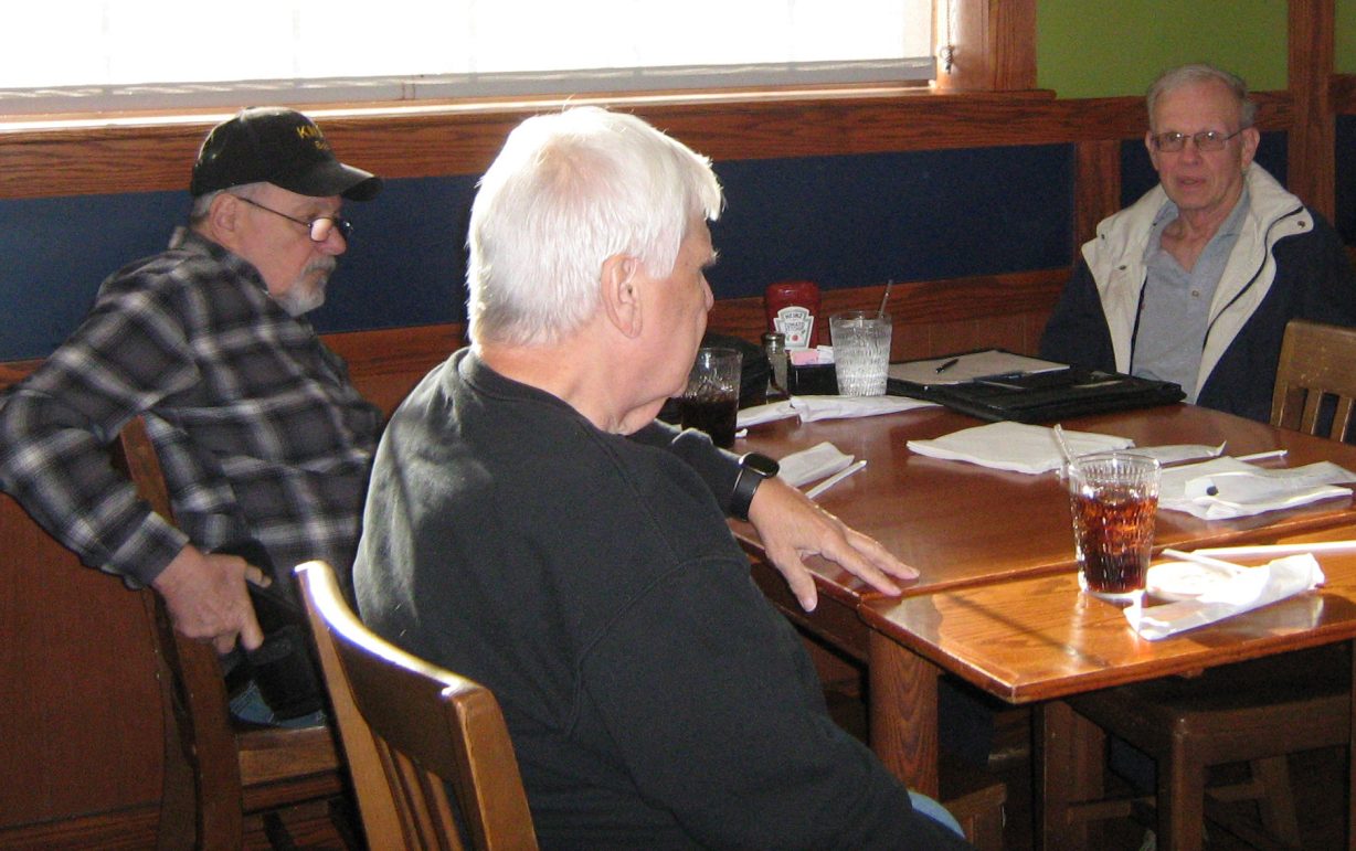 Three men sitting at a table.