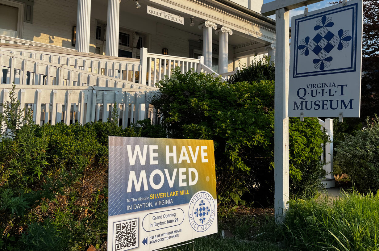 A sign saying "we have moved" outside an old, stately white house.
