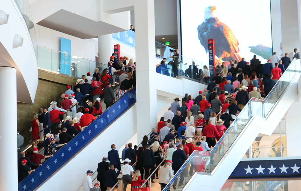 People on steps and an escalator going toward a large image of a bald eagle