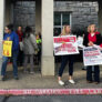 People holding signs saying "A strong collective voice" and "Families for CB" outside a school building.