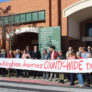 a group of people holding a long homemade sign saying "Rockingham deserves COUNTY-WIDE transit"