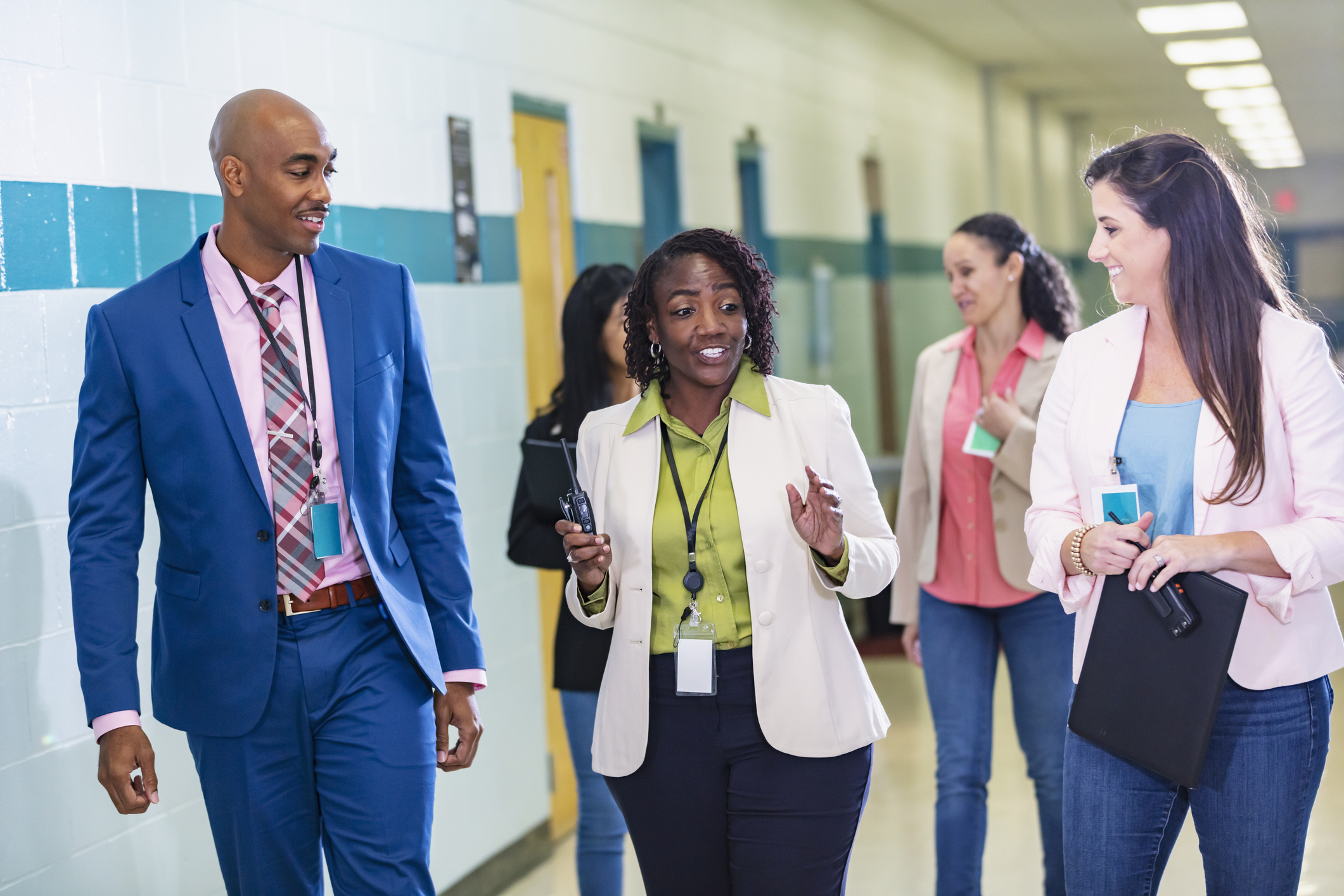 Multiracial group of teachers walking in school hallway. Image credit: iStock