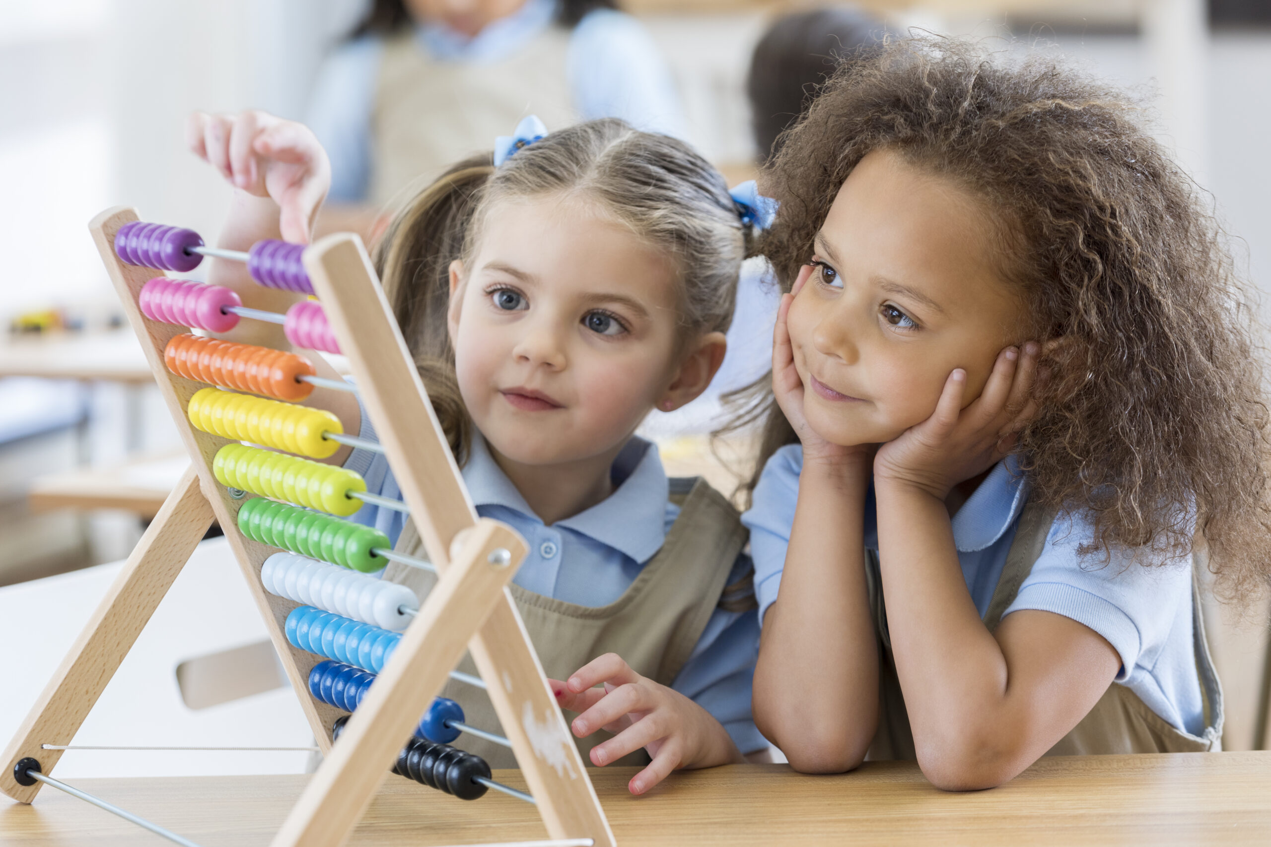 Happy preschool friends enjoy using an abacus during preschool.