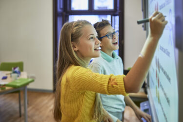 two school friends using the smart board for their project