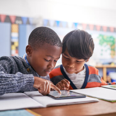 Cropped shot of elementary school children using a tablet in class