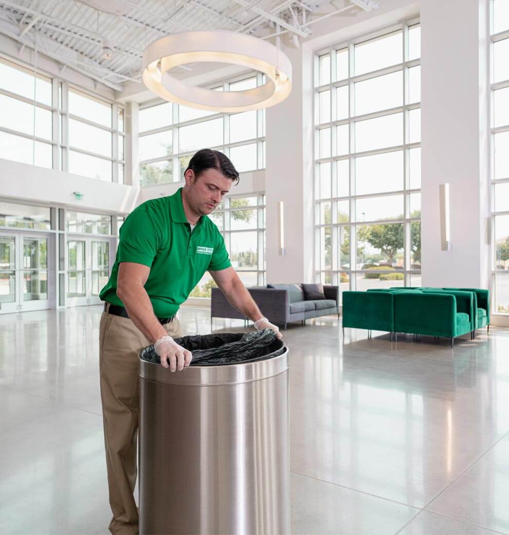 commercial cleaner replacing trash bag in business building entrance area