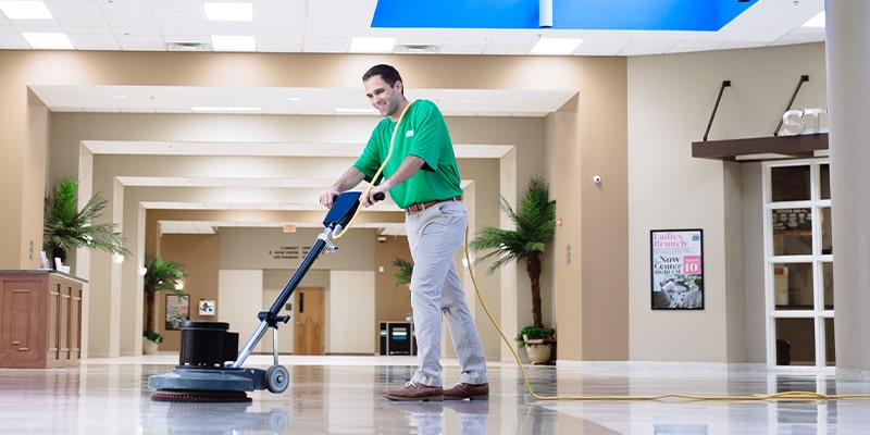 Professional commerical Cleaner buffing the school floors near the entrance way during the summertime while most students are out