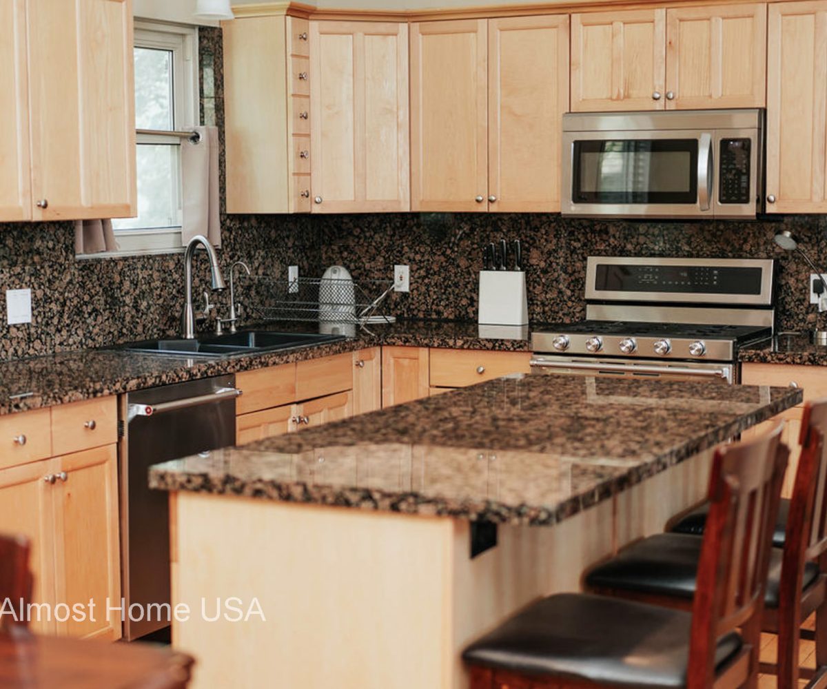 Large kitchen island with granite countertop located in furnished home in Sandy Utah.