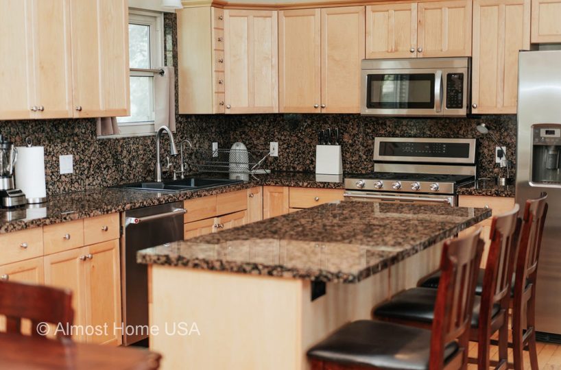 Large kitchen island with granite countertop located in furnished home in Sandy Utah.