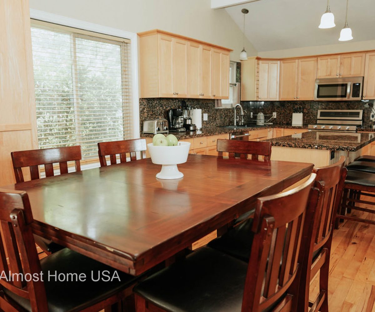 Dining table and kitchen cabinets in furnished home located in Sandy, Utah.