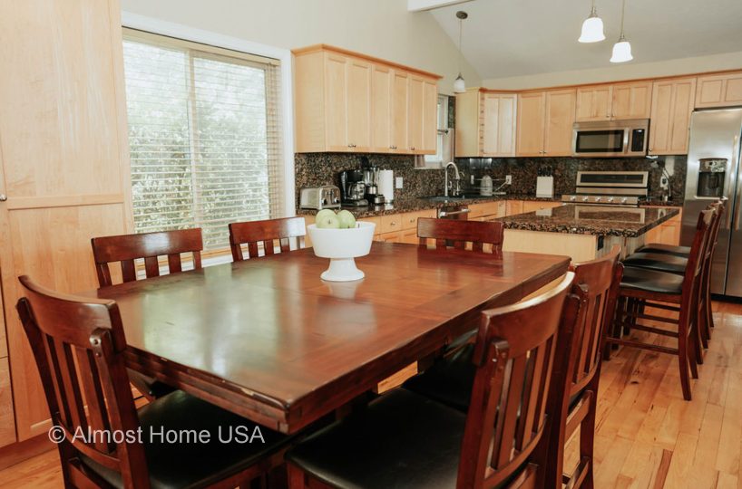 Dining table and kitchen cabinets in furnished home located in Sandy, Utah.