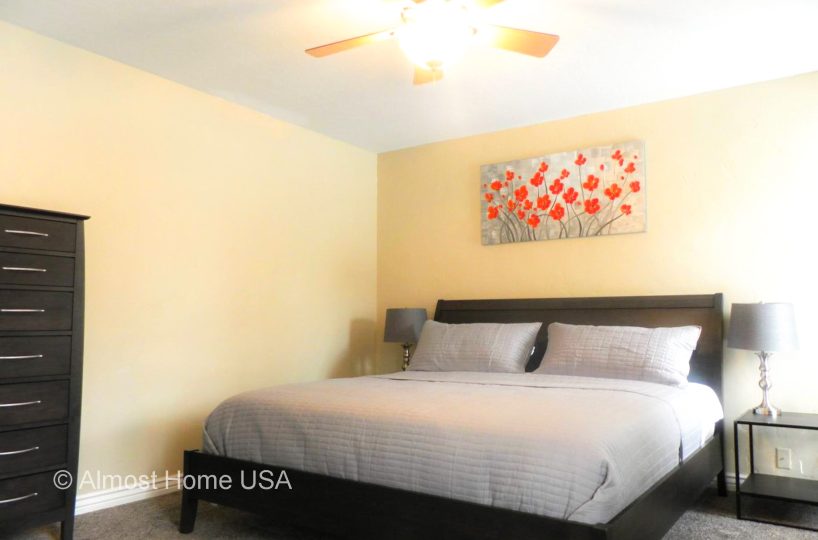 King bed and wall art in master bedroom located in furnished home in Sandy Utah.