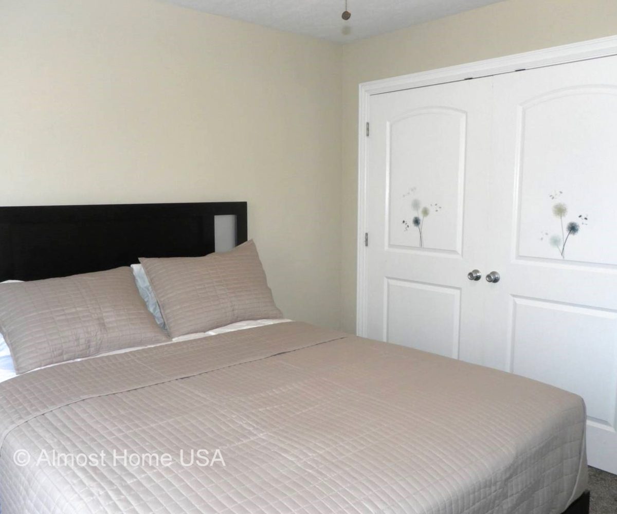 Queen bed in bedroom located in furnished home in Sandy, UT.