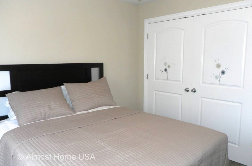 Queen bed in bedroom located in furnished home in Sandy, UT.