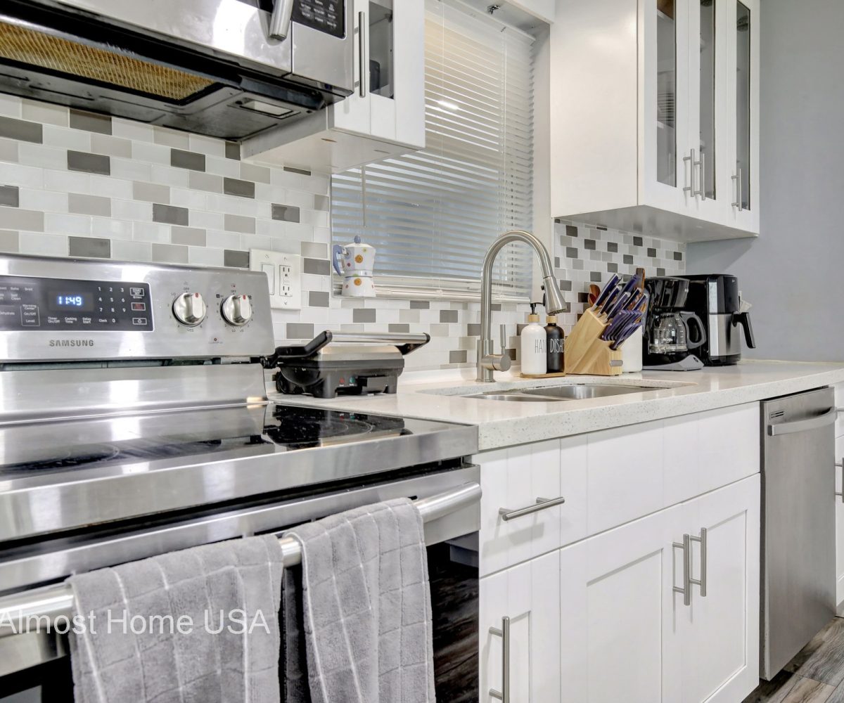 Updated kitchen with stainless steel appliances and backsplash in furnished home located in Miami, FL.