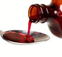 A bottle of cold medicine poured into a spoon