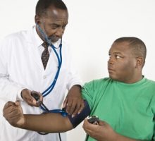 african american doctor taking blood pressure reading of an african american patient
