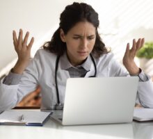 angry female doctor looking at prescription drug ad on her laptop