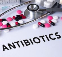 The word antibiotics surrounded by pills and a stethescope