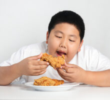Schoolboy eating processed food, becoming obese