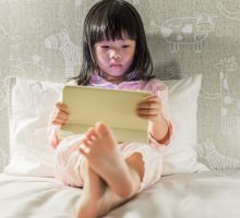 Young child reading a tablet in bed