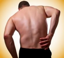 man with back pain holds his back