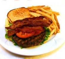 a hamburger with bacon and a side of fries