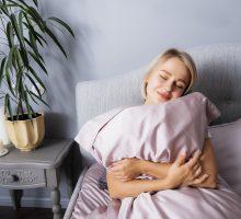 Woman hugs a pillow in bed. Do you love your pillow this much? She will be sleeping a little longer.