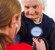 Young doctor measures the elderly woman blood pressure