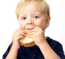 Boy taking a big bite of his peanut butter sandwich