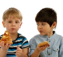 two young boys eating pizza