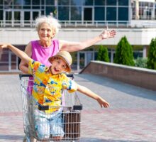 Grandmothers matter for care of grandchild, grandmother rolls happy boy in a shopping cart