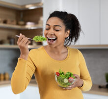 Young pregnant woman eating vegetables to improve pregnancy outcomes