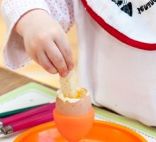 Child dipping toast into a soft boiled egg