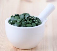 green chlorophyll pills in a ceramic mortar and pestle