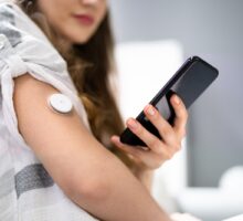 woman using continuous glucose monitor with smart phone