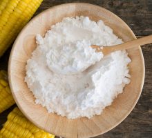Corn starch powder in a spoon a wooden bowl.