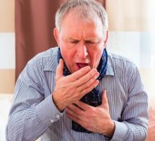 Old man coughing and holding chest having a bad cold