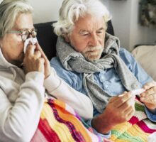 An older couple suffering from the flu or a bad cold or COVID.