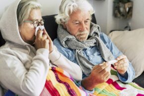 An older couple suffering from the flu or a bad cold or COVID.