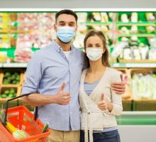 Couple shopping in a supermarket while wearing face masks