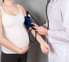 Pregnant woman gets blood pressure measured while standing