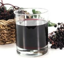 a glass of elderberry juice and elderberries