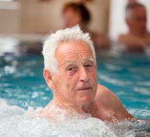 Elderly man enjoying in pool with hot water in spa resort