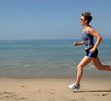 a woman getting exercise by running on the beach