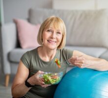 woman making healthy lifestyle changes in diet (green salad) and exercise (fitball)